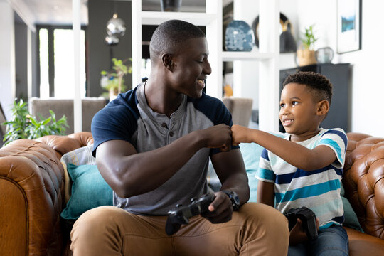 Image of african american father and son playing games on the console