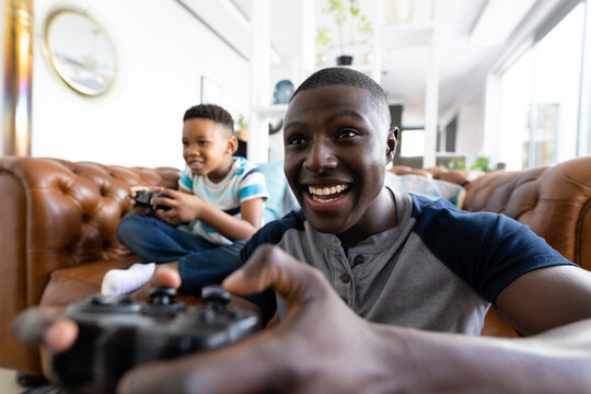 Image of african american father and son playing games on the console