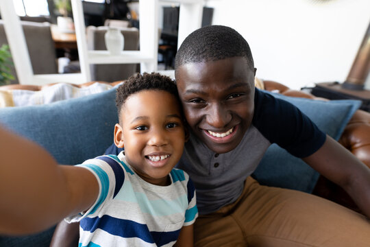 Image of african american father and son taking selfie
