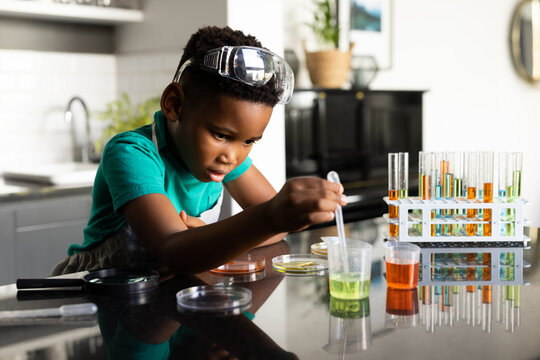 Image of smiling african american boy doing experiments at home