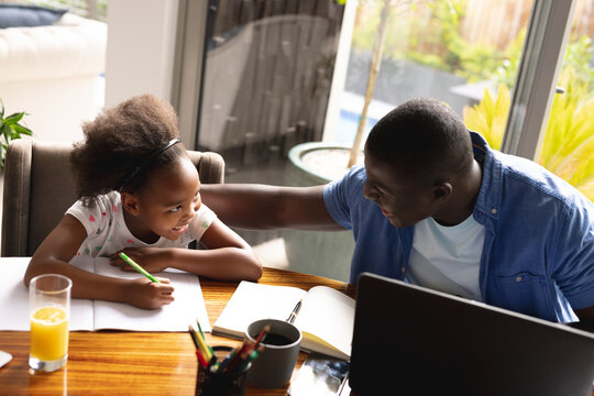 Happy african american father and daughter doing homework and working together