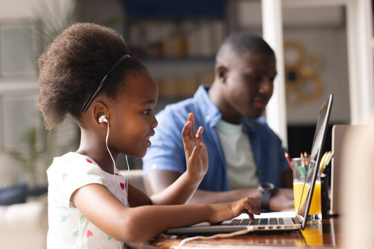 Image of african american father and daughter having online lessons and working together