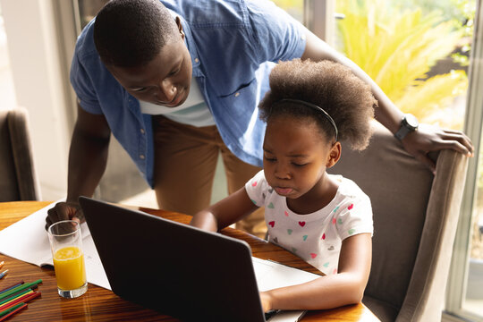 Happy african american father and daughter doing homework together
