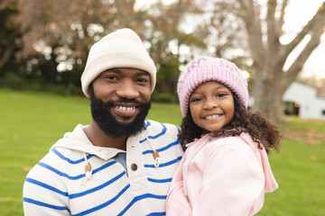 Image of happy african american father and daughter embracing in garden