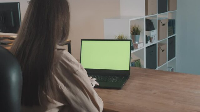 Girl in a modern office working on a laptop with green screen