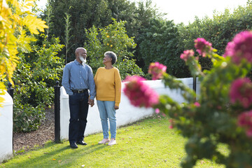 Fototapeta premium Image of happy african american senior couple walking in garden