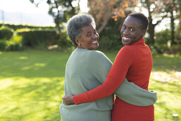Image of happy african american mother and adult daughter posing in garden - Powered by Adobe