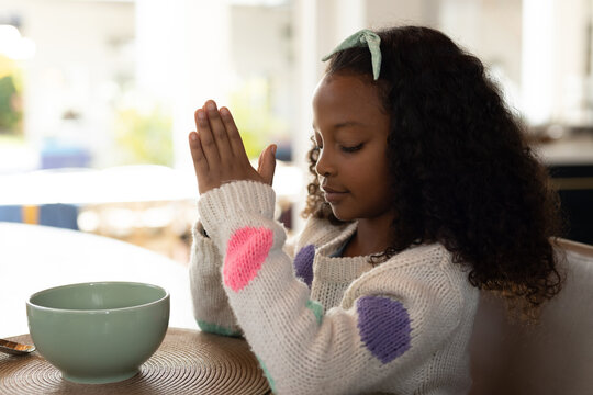 Image of african american girl praying before meal
