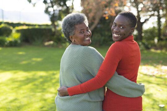 Image of happy african american mother and adult daughter posing in garden