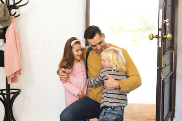 Image of caucasian father returning home from work and welcoming with children