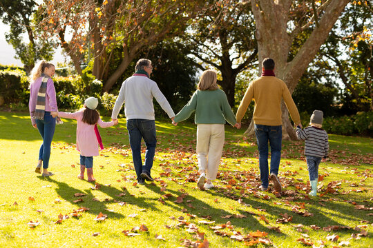 Image of back view of multi generation caucasian family spending time in autumn garden