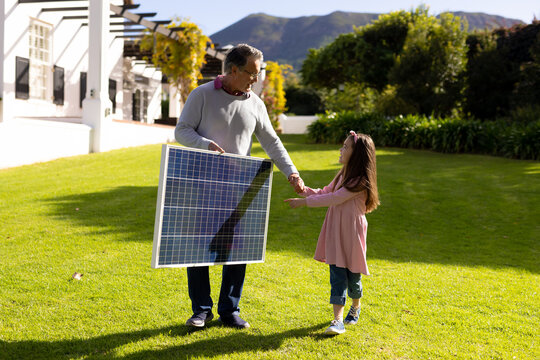 Image of caucasian grandfather with solar panel and granddaughter