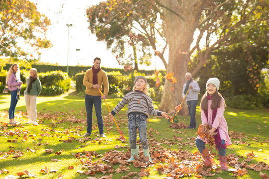 Image of happy multi generation caucasian family having fun with leaves in autumn garden