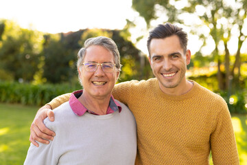 Image of happy caucasian father and adult son in garden