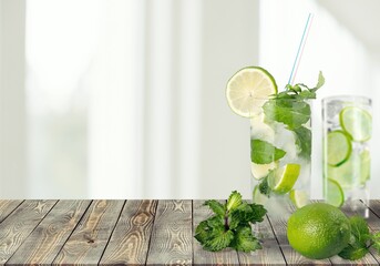 Organic cold refreshing lemonade drink or cocktail made of sparkling water, lime slices and fresh green mint leaves served in drinking glass with ice cubes
