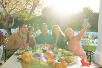 Image of multi generation caucasian family taking selfie after outdoor dinner