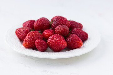Ripe strawberries on a plate on a white background. Summer berries