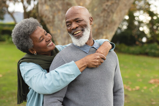 Image of happy african american senior couple posing at camera outdoors in autumn