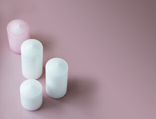 Set of white and pink wax candles on the pink background with copy space