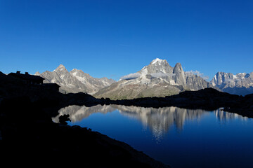 Fototapeta na wymiar First shadows at end of day while mountains are still bright at the Lac Blanc shores.
