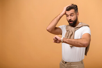 Young handsome business man looking at the watch time worried, afraid of getting late, standing...