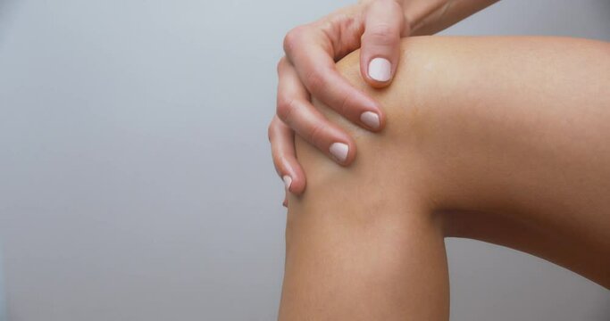 Naked woman applying cream on her knee and caressing her skin.
Isolated shot.