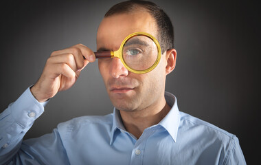 Fototapeta na wymiar Caucasian man holding magnifying glass and looking at camera.
