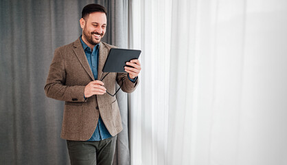 Portrait of smiling cheerful man businessman entrepreneur standing holding tablet and eyeglasses. © Moon Safari