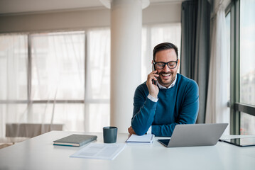 Portrait of young smiling cheerful entrepreneur in casual office making phone call while working.
