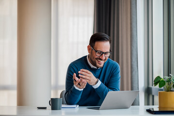 Smiling young manager looking at successful business plan on laptop