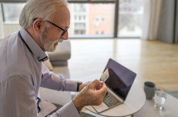 Senior happy smiling handsome man sitting at his home or office using laptop computer.