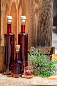 a glass and bottles fresh liquor from the swiss stone pine at a sunny july day with a rustic wood board in the background
