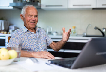 Old man with laptop talking through video call