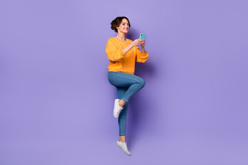 Fototapeta na wymiar Full body portrait of active carefree girl hold telephone chatting write blog post isolated on purple color background