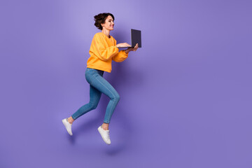 Full length body size view of attractive focused girl jumping using netbook writing email isolated over violet lilac color background