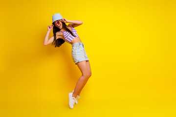 Fototapeta na wymiar Full length photo of pretty cool lady wear striped crop top cap dark spectacles dancing empty space isolated yellow color background
