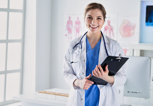 Smiling female doctor with a folder in uniform standing