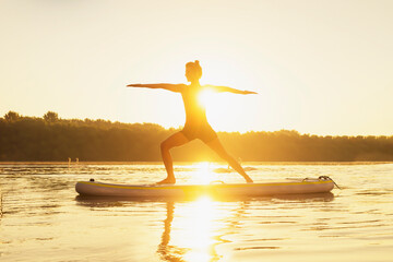 Young woman practicing yoga to calm cool herself down on a paddle board during a summer heatwave