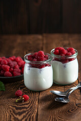 yogurt with raspberry and two spoons on the wooden table