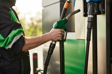 Crop worker putting nozzle into gas petrol dispenser