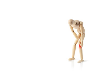 Wooden man holds his hands on sore knee isolated on white background. Concept of pain in the knee. Having knee ache. Copy space.