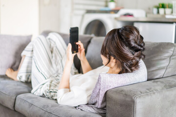 部屋でスマホを使う若い女性