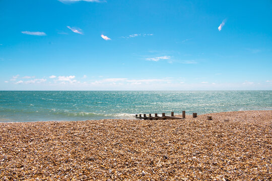 Shades of blue. A day in the british south coast, in Felpham, near brighton. View of the beach of pebbles or rocks ,bright blue sea and sky, sunny day. Beautiful summer day in Britain.