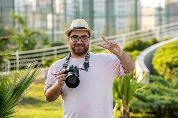 photographer in hat at park with camera professional guy on the photoshoot sending peace