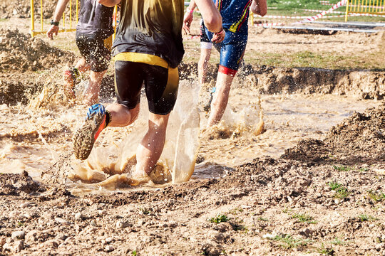 Group of participants in an obstacle course race running across a pool of water. Spartan race