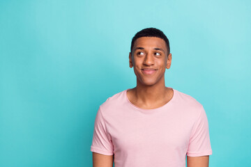 Photo of positive dreamy young man dressed pink t-shirt looking empty space isolated turquoise color background