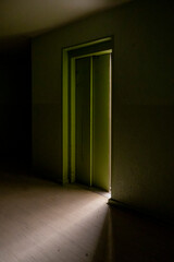 Elevator door opens illuminating dark hallway in Berlin social apartment building 