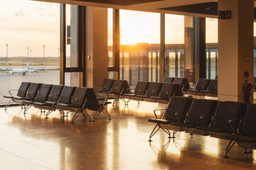 Sun sets outside of empty modern airport departures lounge