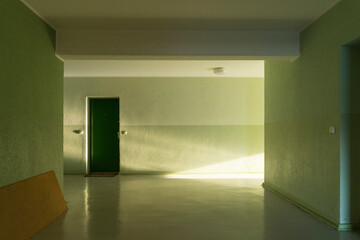 Early morning sunlight shines through window into green painted hallway of East Berlin Apartment block 