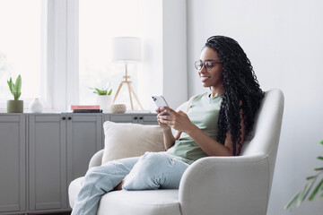 Young woman resting at home with smartphone, beautiful girl looking at phone indoor, Online communication, relaxation, connection, social distancing, technology, leisure lifestyle concept